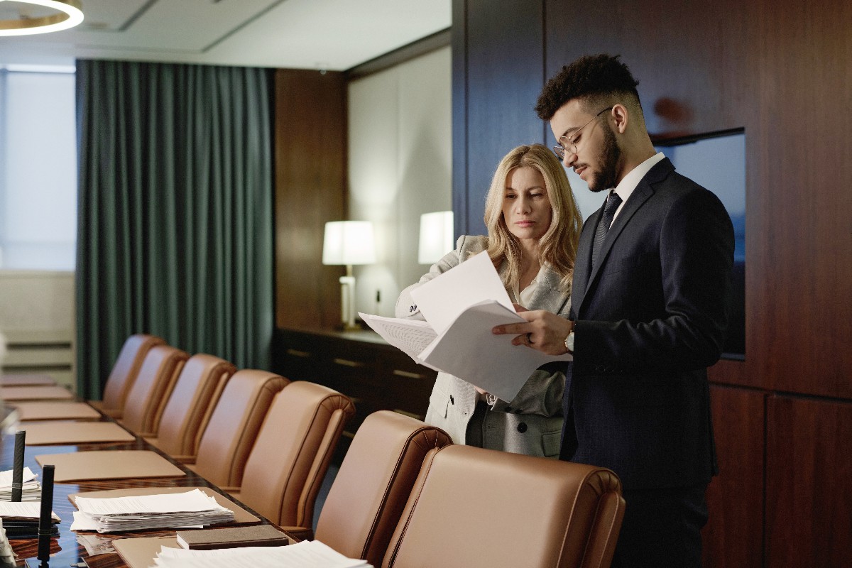 Two businesspeople discussing conference meeting room etiquette while looking at documents
